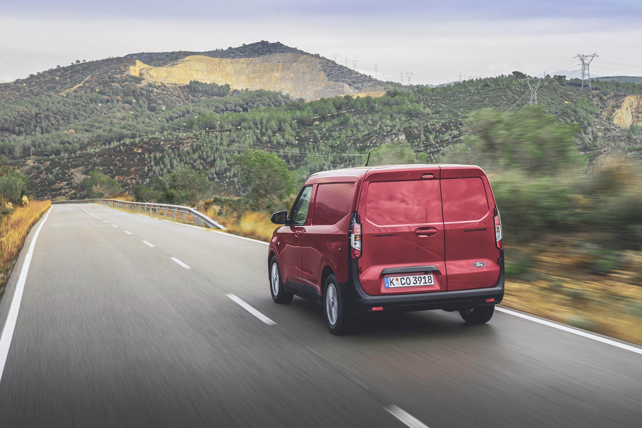 A red van pictured from the back driving on a road.