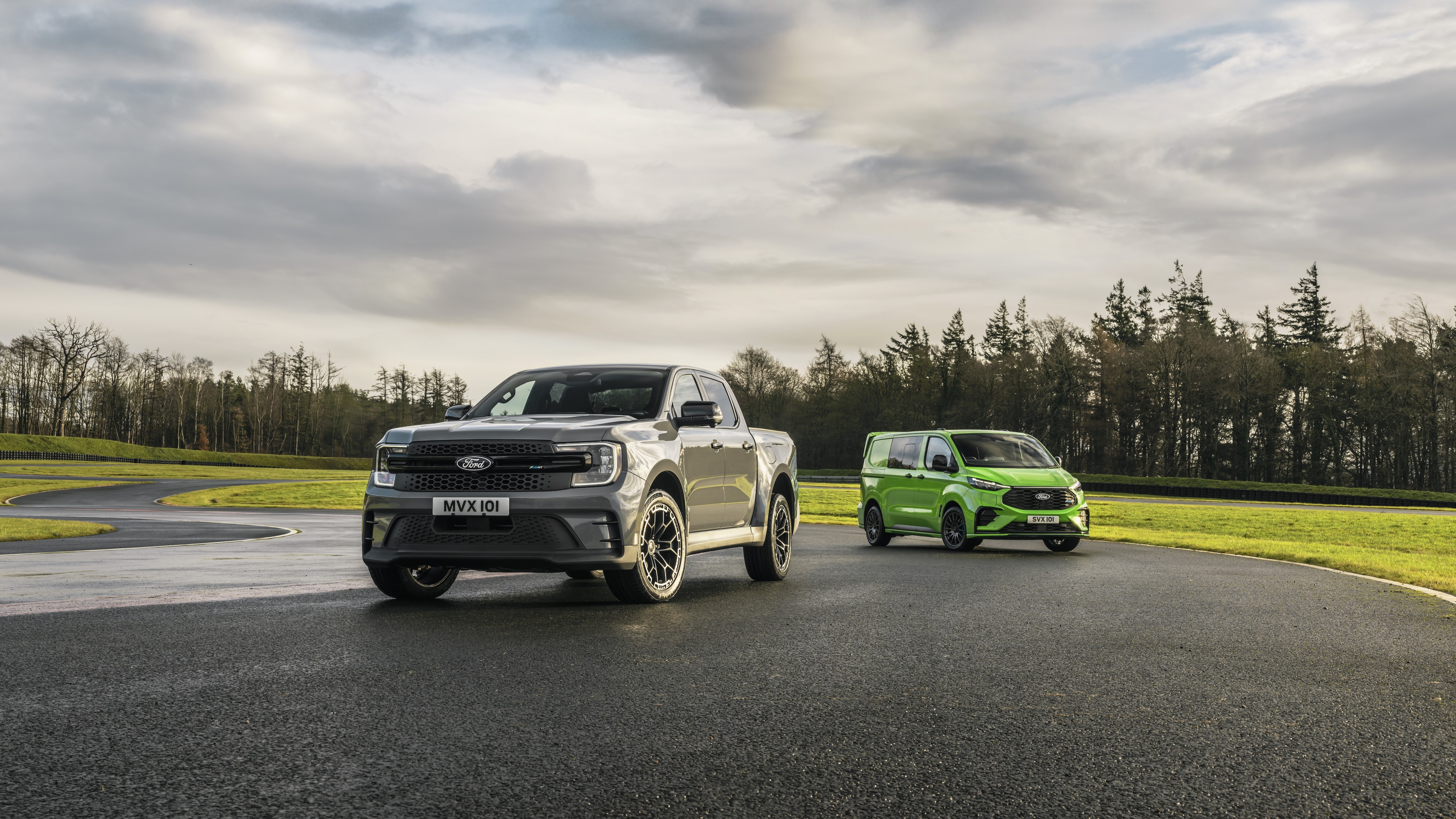a grey pickup on a racetrack with a green van