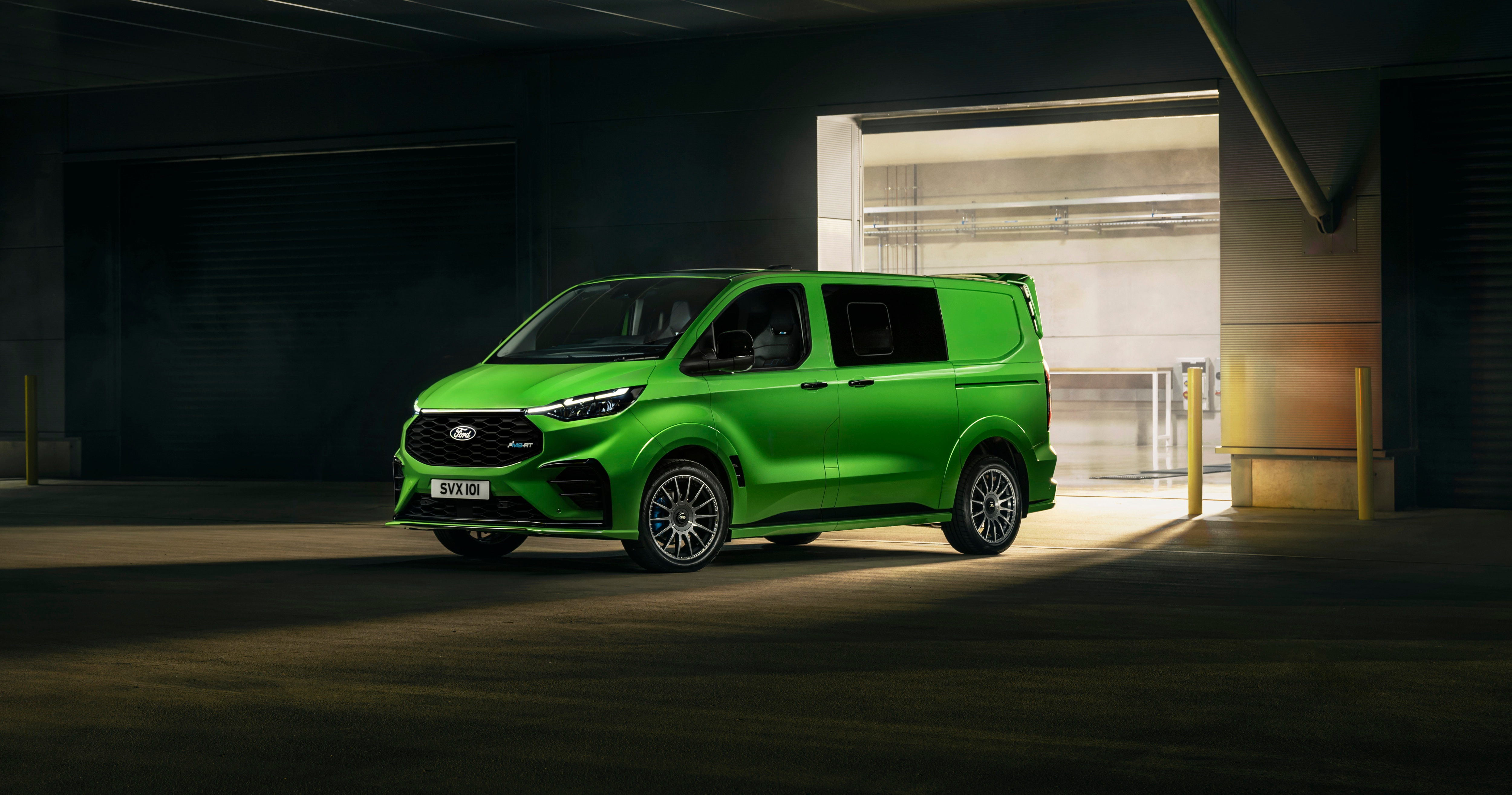 a green van at night illuminated by the lights of a warehouse