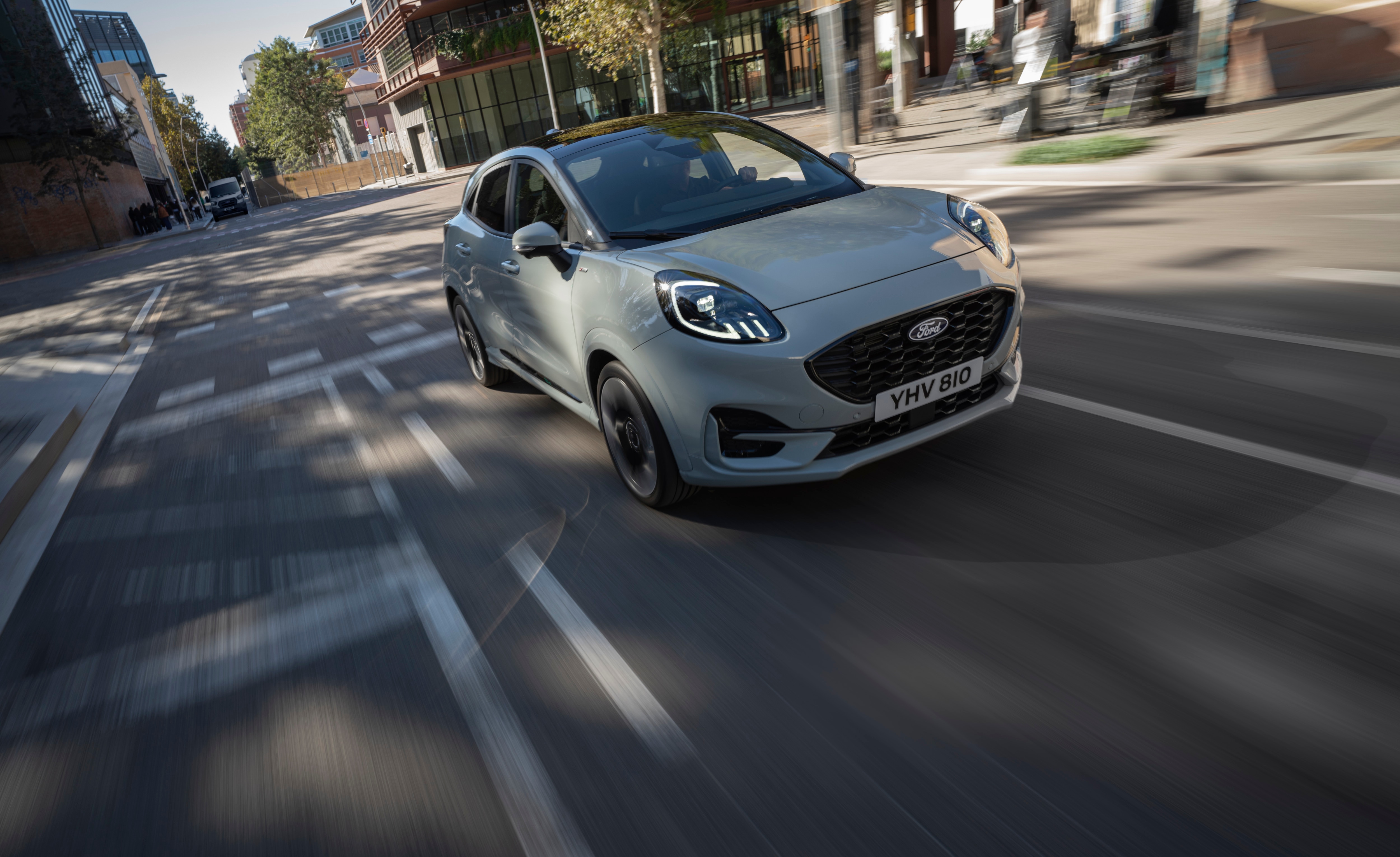 a grey car going down a city street