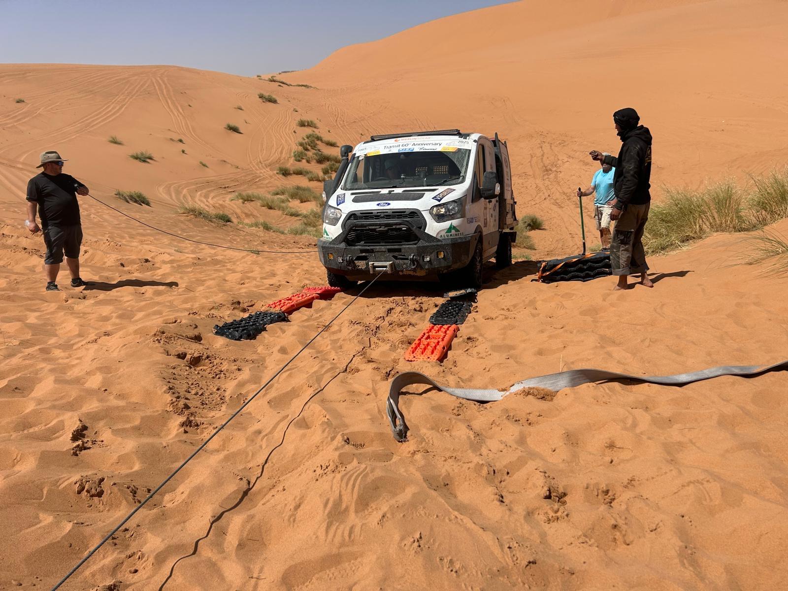 Transit with sand straps and people digging it out of soft sand