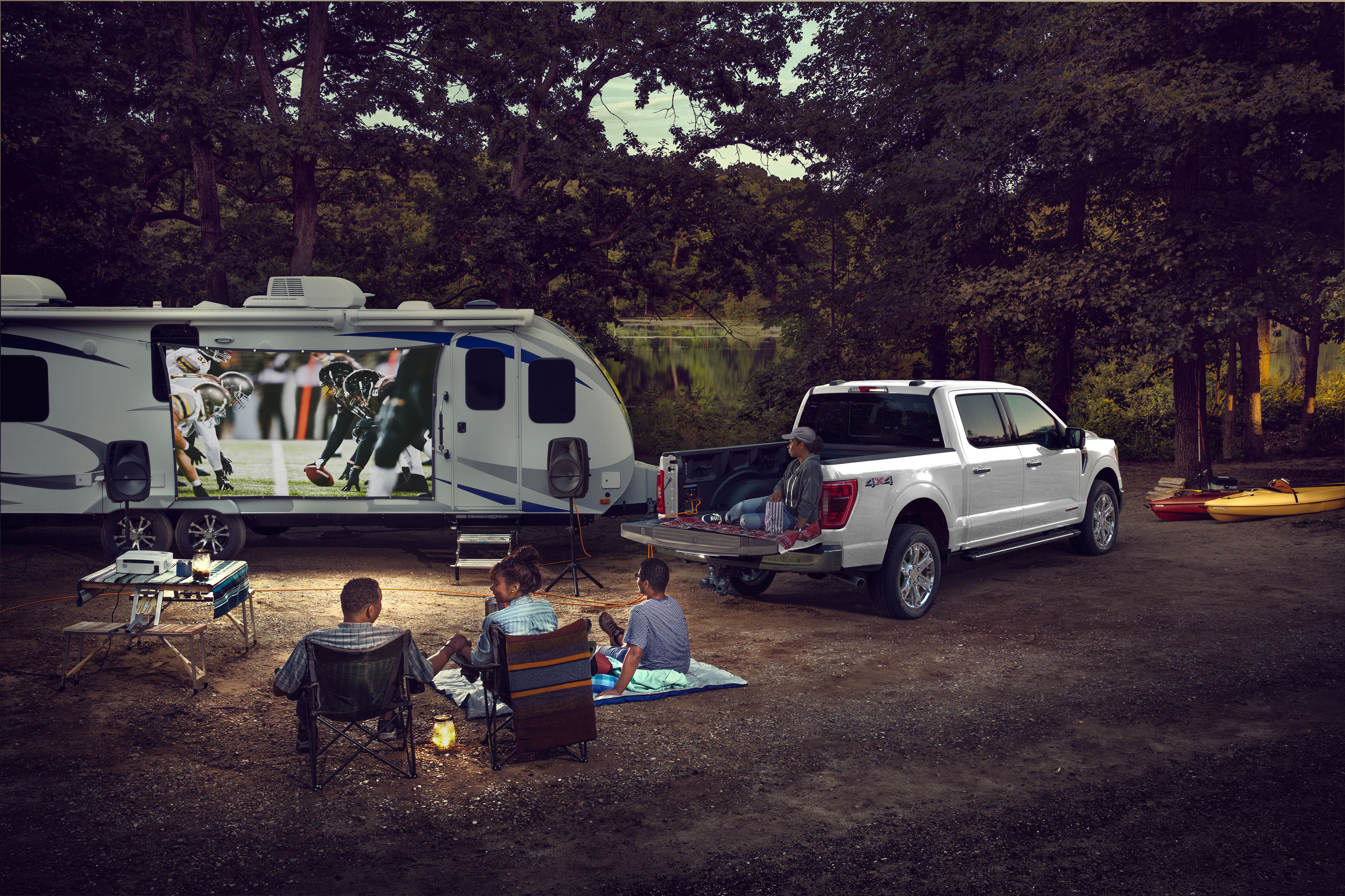 An F-150 demonstrates Pro Power Onboard with a family watching a movie projected on a camper