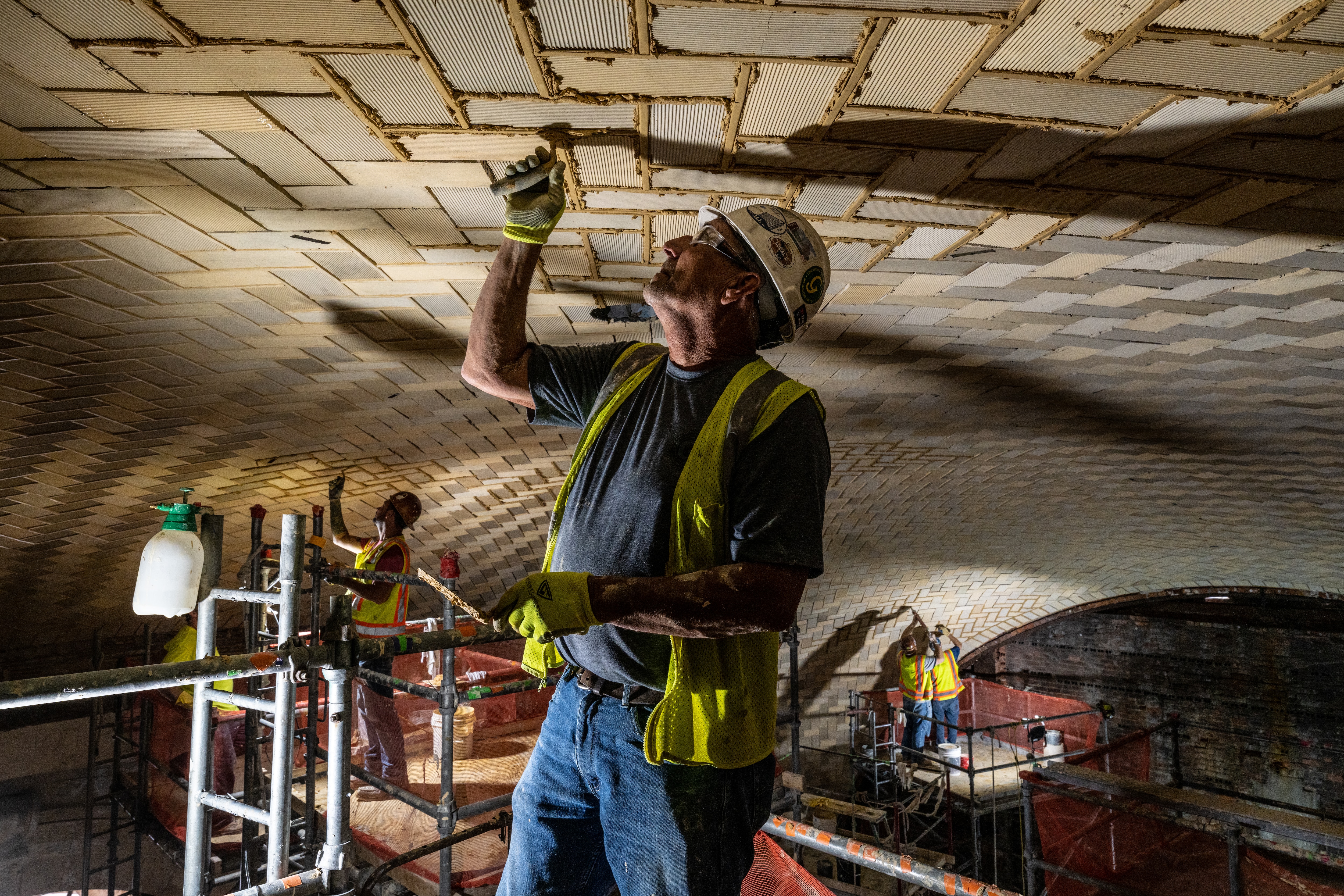 A man in construction gear works on the ceiling at Michigan Central Station