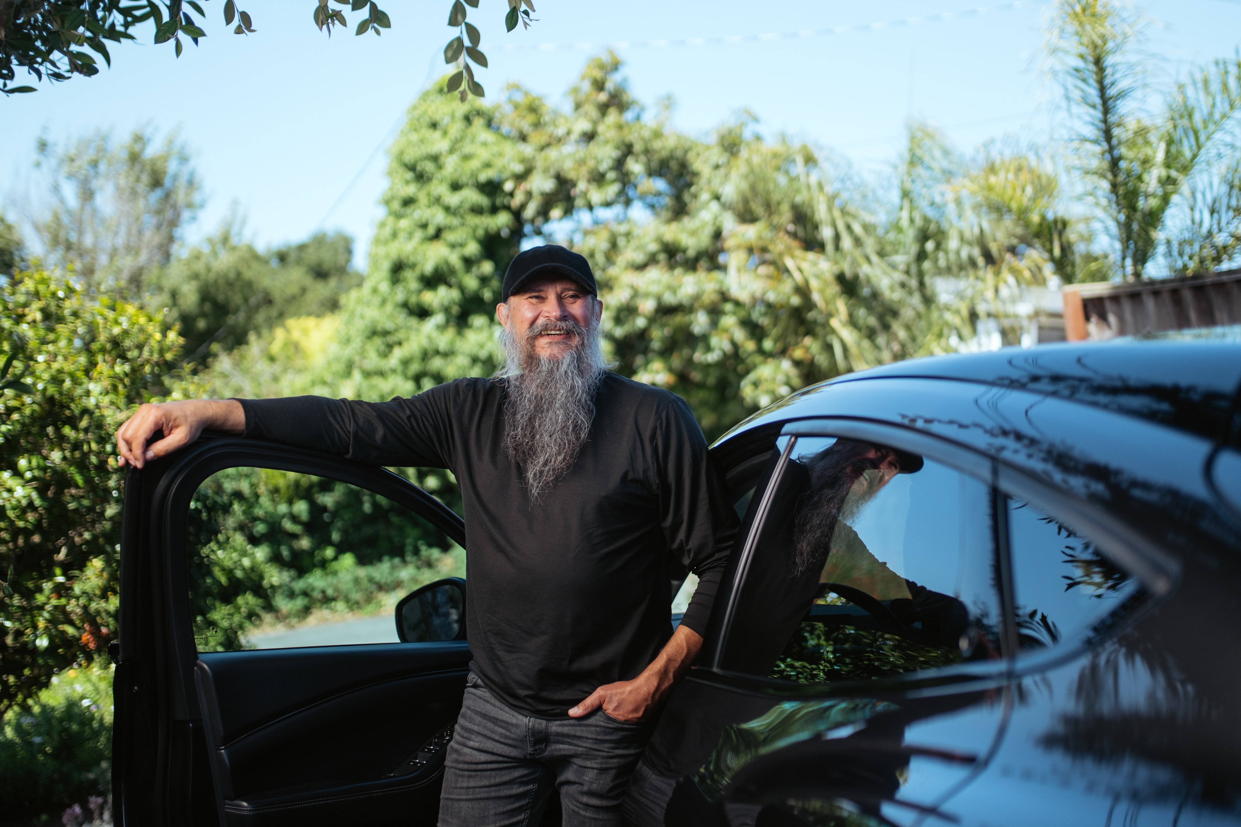 A man poses with his arm on the open car door of his 2022 Mustang Mach-E Premium