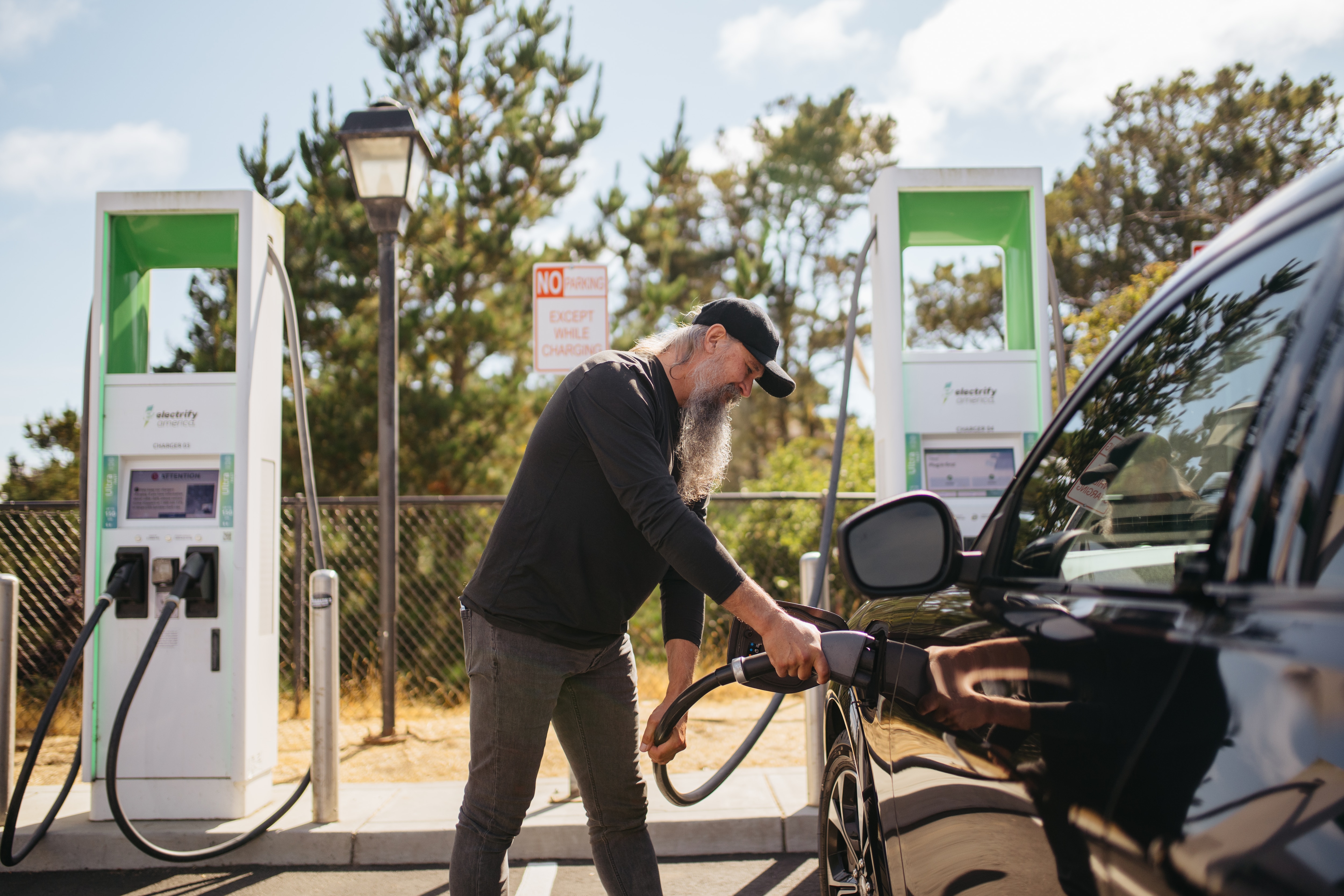 A man charges his 2022 Mustang Mach-E Premium at a public charger