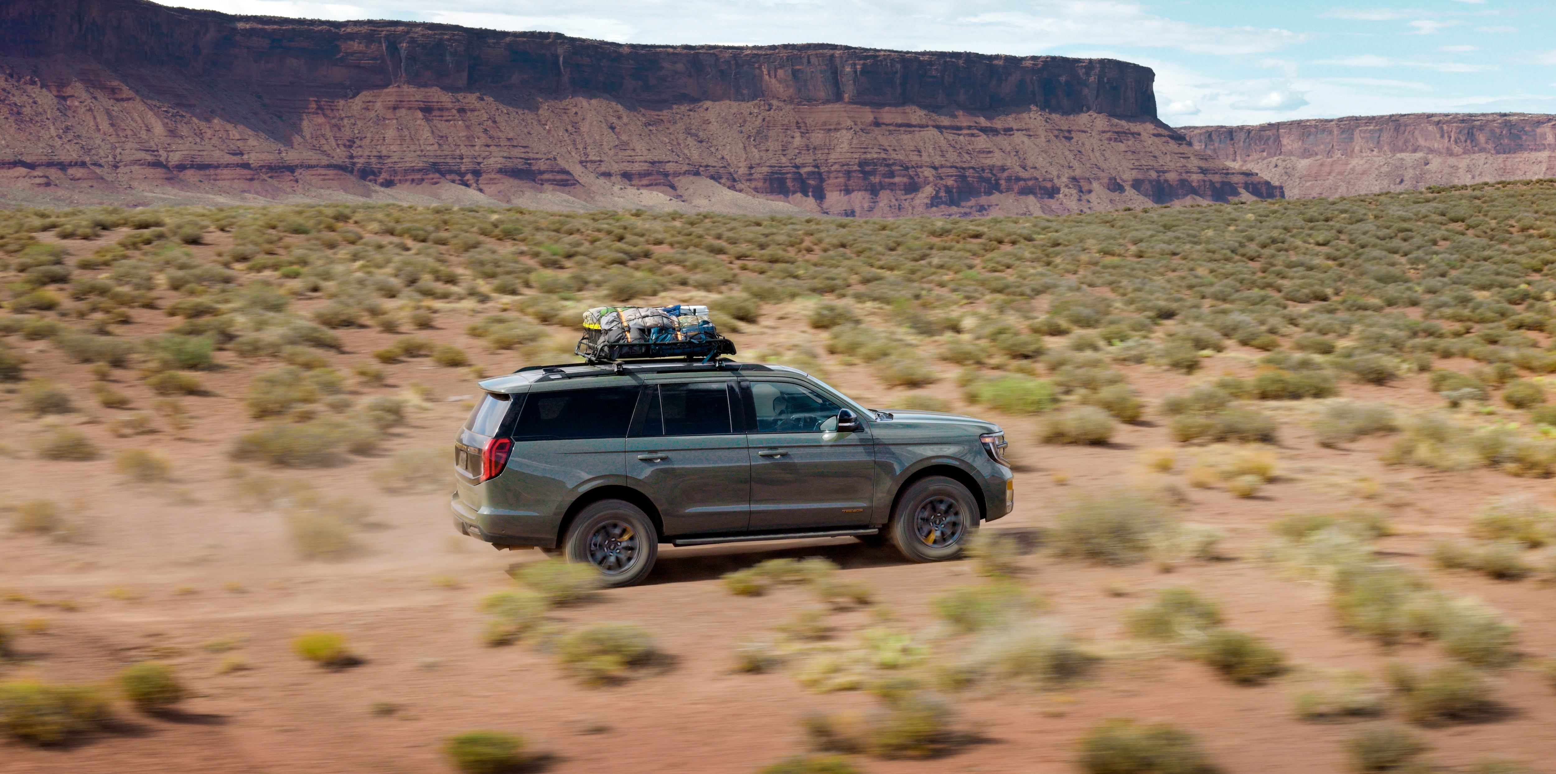 2025 Ford Expedition Tremor with gear strapped to the top driving on rugged terrain