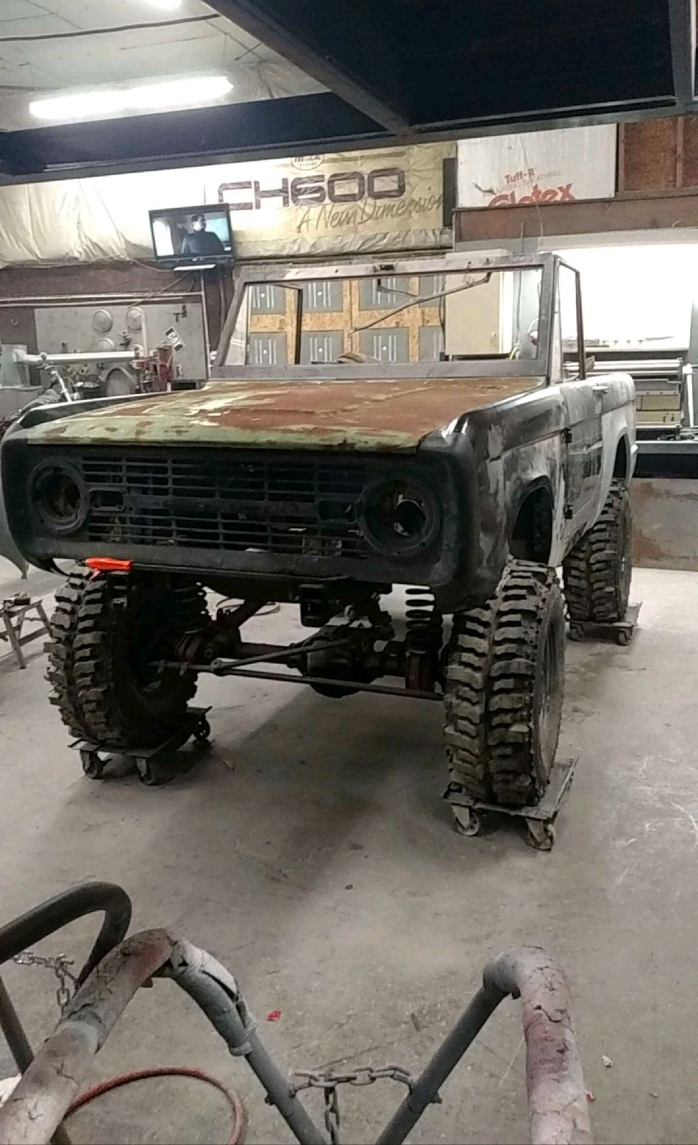 An old Bronco sits in a garage.