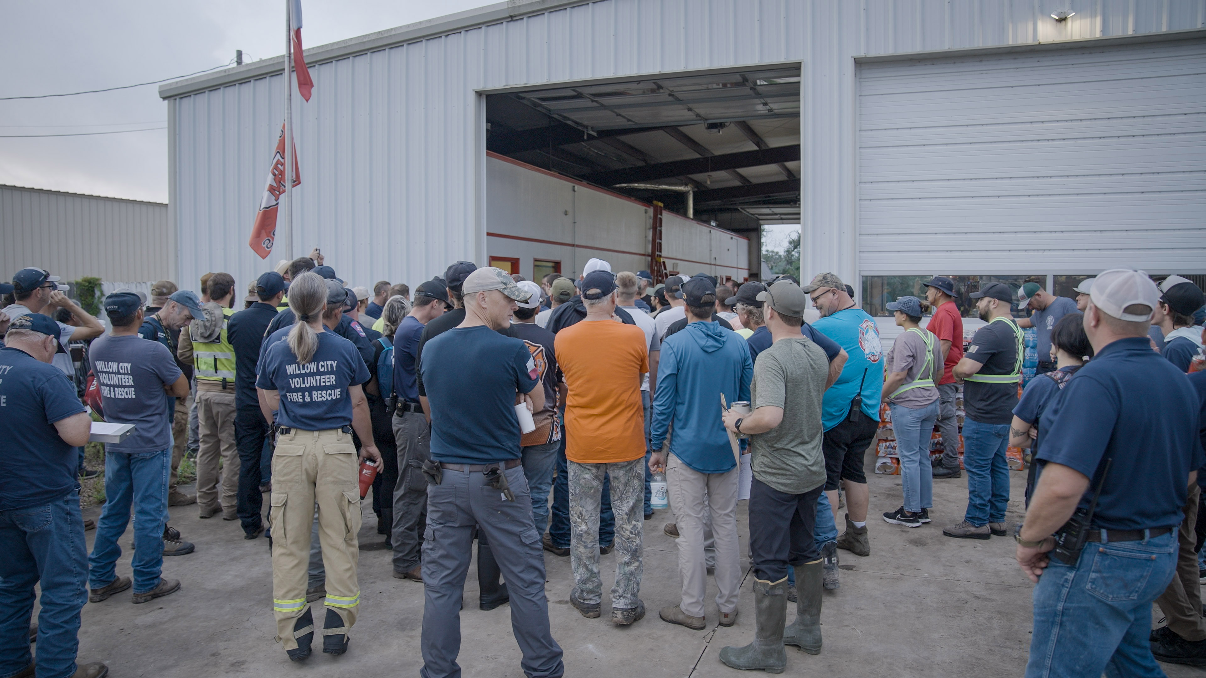 A group of volunteers gather outside of a warehouse.