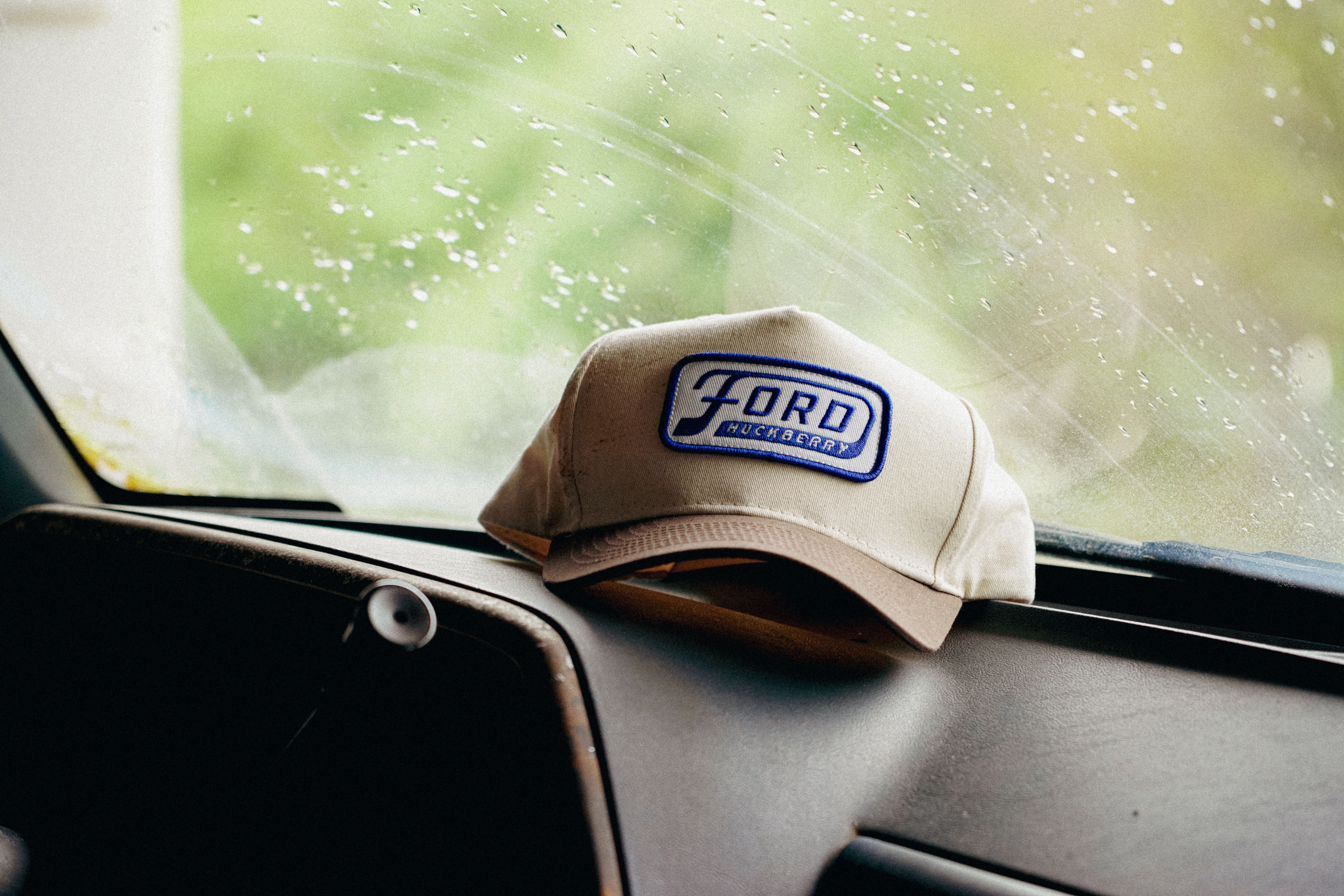 A Ford branded hat sits on the dashboard of a truck