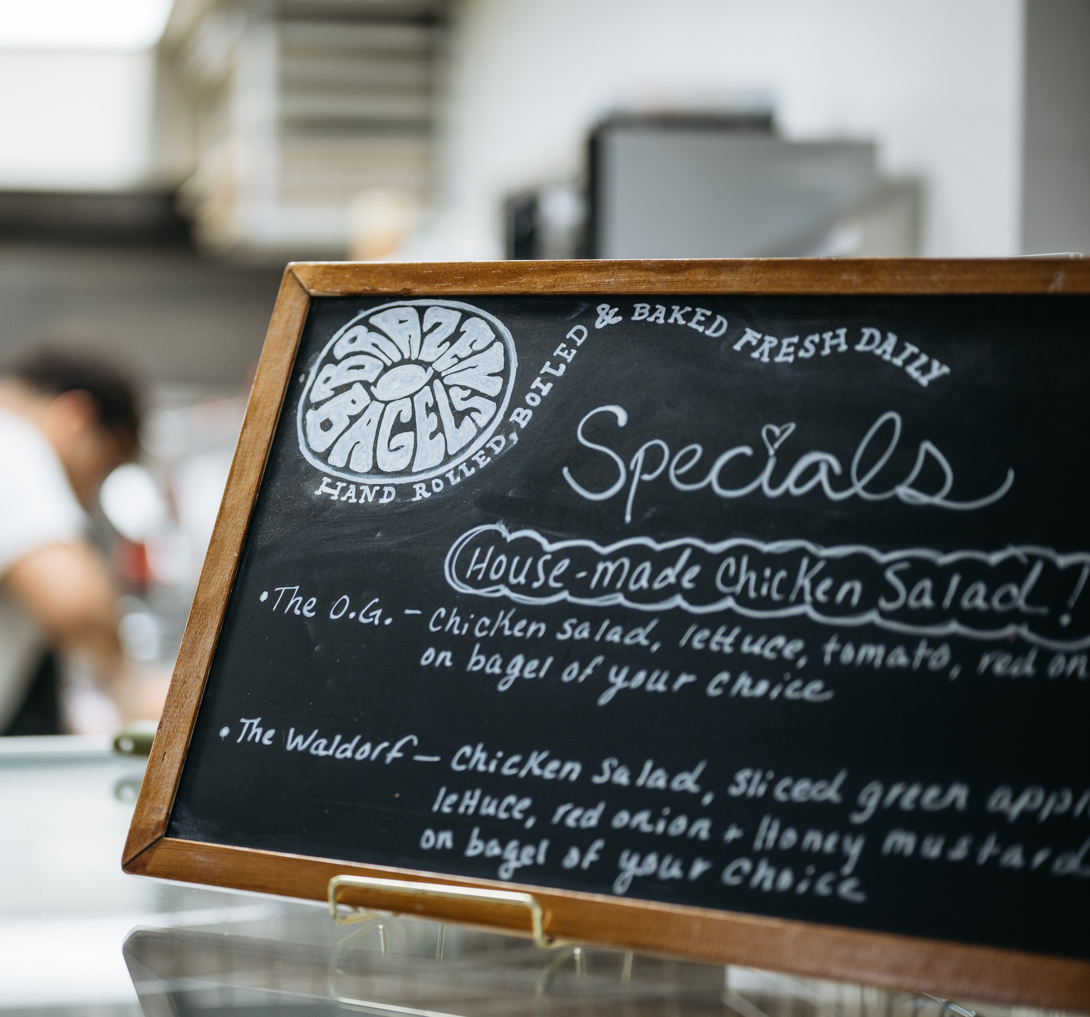 A menu is displayed on the countertop at Brazen Bagels.